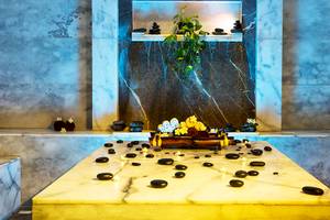 Behandlungsbereich im Jaz Aquaviva Spa mit Marmortisch, schwarzen Steinen und Kerzen.
