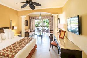 Hotelzimmer im Barcelo Maya Palace mit Bett, Wohnzimmer und Terrassentür.