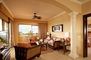 Ein Hotelzimmer mit einer Familie, die auf einem Sofa sitzt und einen Blick auf das Meer genießt.
