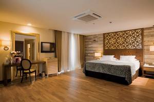 Ein Schlafzimmer im Melas Lara Hotel mit einem großen Bett, Dekor und Möbeln.