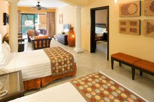 Zwei Doppelbetten in einem Zimmer des Barcelo Maya Palace Hotels, umgeben von Möbeln und Dekor.
