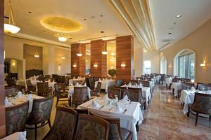 Innenansicht des Restaurants im Melas Lara Hotel mit gedeckten Tischen und Holzsäulen.