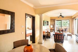 Wohnzimmer im Barcelo Maya Palace mit Möbeln, Teppich, Fernseher, Spiegel und Deckenventilator.