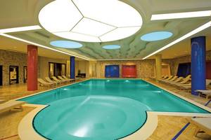 Innenpool des Melas Lara Hotels mit Loungeliegen und bunten Säulen.