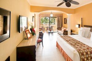 Schlafzimmer im Barcelo Maya Palace Hotel mit großem Bett, Fenstern und Terrassenzugang.
