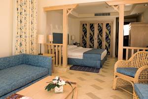 Hotelzimmer im Grand Hotel Sharm El Sheikh mit Bett, Sofa, Tisch und Dekoration.