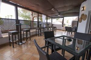 Innenansicht der Terrasse des Cala Martina by Llum Hotels mit Tischen, Stühlen und Sonnenschirmen.