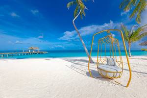 Strand mit Hängematte und Hotel Sun Siyam Iru Veli im Hintergrund
