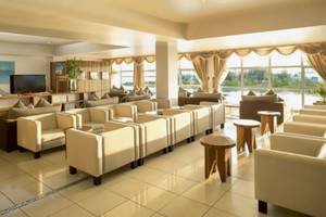 Lounge-Bereich des Sun Siyam Iru Veli Hotels mit weißen Möbeln, einem Fernseher und großen Fenstern.