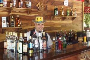 Ein Barkeeper im ROC Arenas Doradas Hotel steht hinter einer Bar mit vielen Alkoholflaschen.