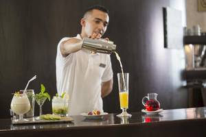 Ein Barkeeper im Hipotels La Geria Hotel schenkt Cocktails in Gläser ein.