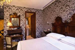 Schlafzimmer im Casa Nicolo Priuli Hotel mit Bett, Nachttisch, Stuhl und Wanddekoration.