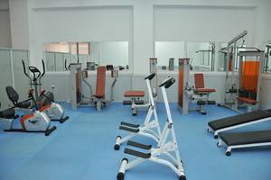 Fitnessstudio im Mastichari Bay Hotel mit verschiedenen Geräten auf blauem Boden.