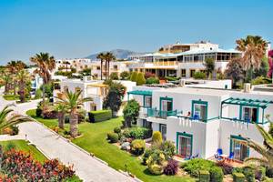 Luftaufnahme des Mastichari Bay Hotels mit weißen Gebäuden, blauen Balkonen und grünen Gärten.
