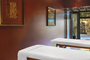 Massageraum im Le Meridien Ile Maurice Hotel mit zwei weißen Massageliegen und dekorativen Rahmen an der Wand.