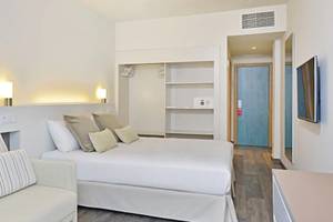Innenansicht eines Hotelzimmers im Sol Barbados mit einem Bett, Sofa, Lampen und Fernseher.