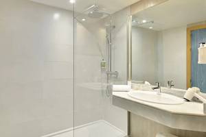 Badezimmer im Sol Barbados Hotel mit Glasdusche, Waschbecken und Spiegel.