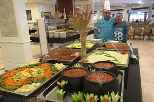 Buffet im Riviera Hotel & Spa mit verschiedenen Gerichten und zwei Männern im Hintergrund.