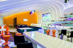 Innenansicht der Lounge im Temptation Cancun Resort mit geschwungener Decke, orangefarbenen Wänden und moderner Einrichtung.