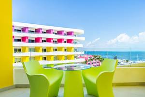 Ausblick von der Balkon des Temptation Cancun Resorts auf das Meer und eine bunte Hotelfassade.