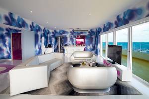Wohnzimmer im Temptation Cancun Resort mit blauen und weißen Wänden, weißen Möbeln und Blick auf das Meer.