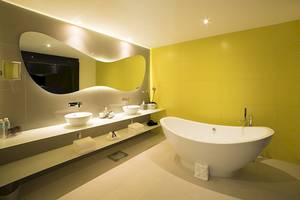 Ein modernes Badezimmer mit zwei Waschbecken, einer Badewanne und gelben Wänden.