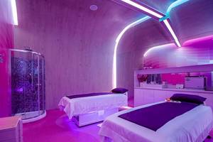 Zwei Betten im Temptation Cancun Resort Behandlungsraum mit lila Beleuchtung und modernem Design.