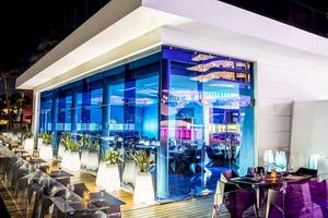 Außenbereich des Temptation Cancun Resorts bei Nacht mit blauen Lichtern und runden Tischen.