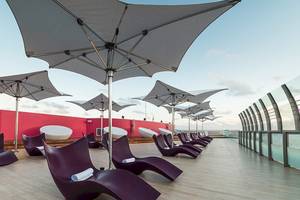 Loungebereich im Temptation Cancun Resort mit roten Liegen und weißen Sonnenschirmen.