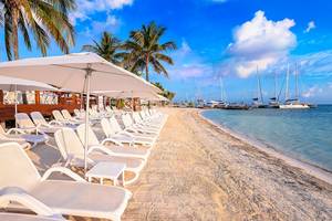 Strand des Temptation Cancun Resorts mit weißen Sonnenliegen und großen Sonnenschirmen