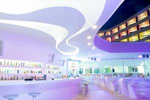 Innenansicht der Bar im Temptation Cancun Resort mit modernem Design, geschwungenen Strukturen und vielen Getränkeflaschen.