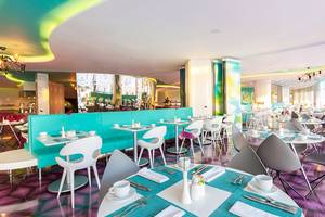 Innenbereich des Restaurants im Temptation Cancun Resort mit blauen und pinken Mustern, weißen Tischen und Stühlen.