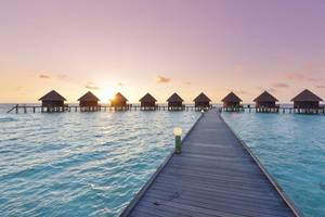Thulhagiri Island Resort Wasserbungalows bei Sonnenuntergang mit rosa Himmel