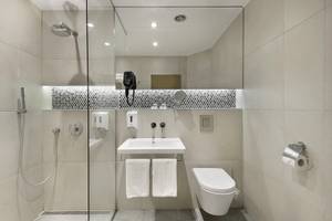 Badezimmer des HVD Club Bor Hotels mit Glasdusche, Toilette und Waschbecken.