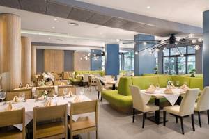 Innenansicht des Restaurants im HVD Club Bor mit grünen Sofas und gedeckten Tischen.