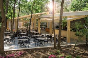 Terrasse des HVD Club Bor Hotels mit Tischen, Stühlen und Bäumen.
