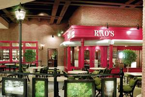 Innenansicht des RAO's Restaurants im Caesars Palace mit roten Wänden, Tischen und Stühlen sowie Bildern auf den Stühlen.