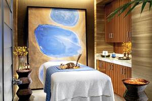 Spa-Behandlungsraum im Caesars Palace mit einem großen Wandgemälde, einem Behandlungstisch, Blumenvase, Kerzen und ätherischen Ölen.