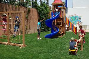 Kinder spielen auf einem Spielplatz im Freien im Monachus Hotel & Spa.