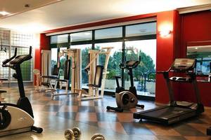 Fitnessraum im Miramare Beach Hotel mit verschiedenen Trainingsgeräten und Blick auf die Außenanlagen.