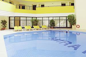 Poolbereich im Miramare Beach Hotel mit gelben Sonnenliegen und blauem Wasser.