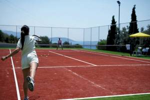 Tennisplatz im Proteas Blu Resort mit einer Frau, die den Ball schlägt.