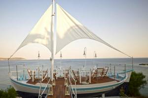 Bootsrestaurant im Proteas Blu Resort mit Tisch und Stühlen am Meer