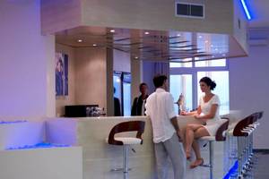 Ein Paar steht an der Bar im Proteas Blu Resort, während zwei Personen im Hintergrund stehen.