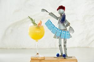 Ein Getränk in einem Glas mit griechischem Motiv neben einer Statue