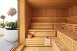Innenansicht einer Sauna im Ritz Carlton Abu Dhabi mit Holzbänken, einem Eimer und einem Handtuch.