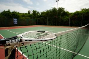 Tennisplatz im Bluebay Beach Resort & Spa mit Netz und Schläger.