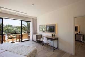 Innenansicht eines Hotelzimmers im Venus Beach Hotel mit Doppelbett, Schreibtisch und Balkon.