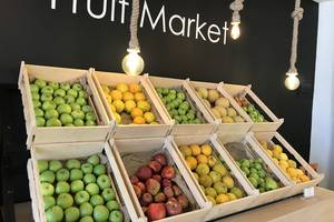 Eine Tafel mit verschiedenen Obstsorten wie Äpfeln, Orangen und Mandarinen in Kisten.