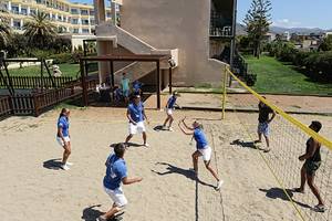 Mehrere Personen spielen Volleyball auf dem Sandplatz des Aphrodite Beach Clubs.
